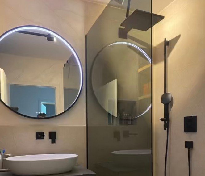 Bad mit rundem LED-Spiegel und Regendusche